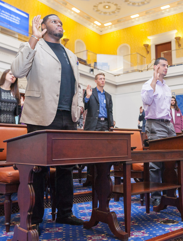 students taking an oath in a replica senate chamber