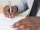 person signing a document with a pen