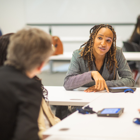 newman fellow seated at classroom table