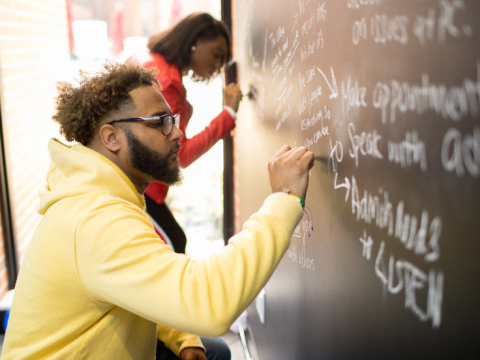 student writing on chalk board