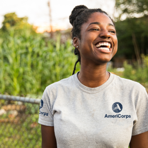 Person wearing an AmeriCorps shirt surrounded by natural greenery