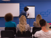 person writes on flip chart at front of classroom