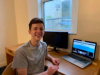 john painter sits at a desk in front of a laptop