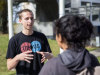 man wearing up to us t-shirt speaks to a woman on a college campus