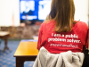 newman fellow wearing an "I am a public problem solver" shirt